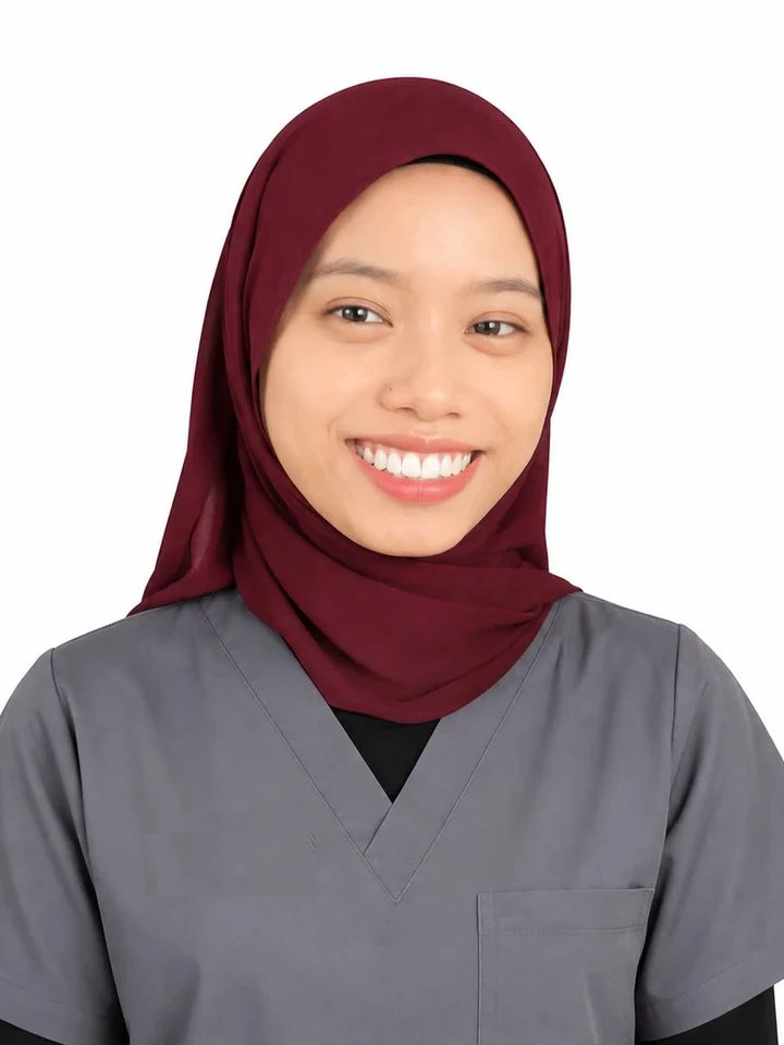 Dental surgery assistant in a maroon hijab and grey scrubs